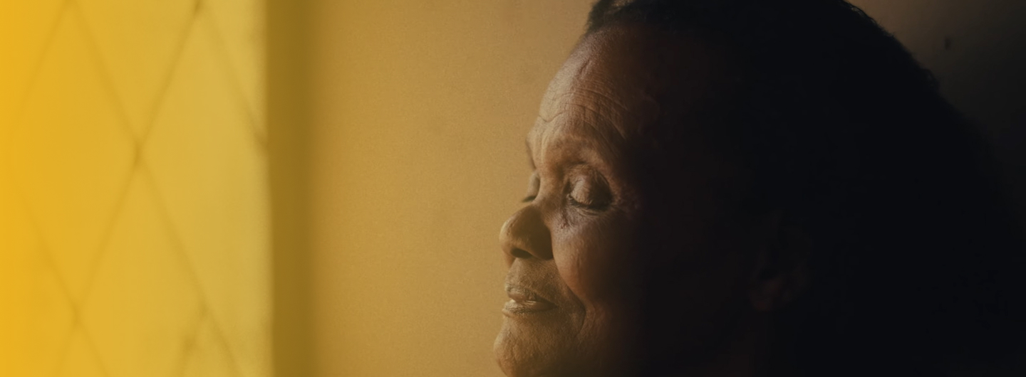 Babize Bonke Photo of a Gogo sitting by the window embracing the light on her face.